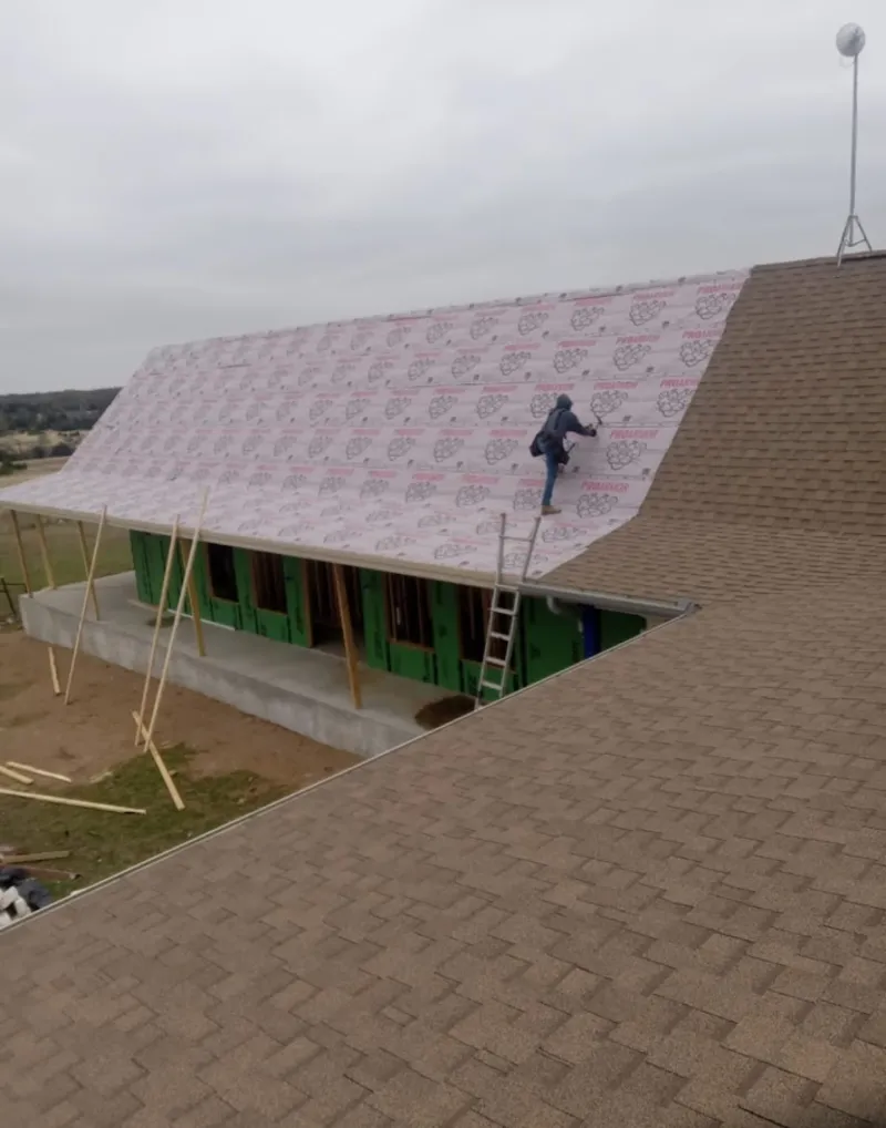 Worker preparing underlayment for a metal roof installation in Benbrook